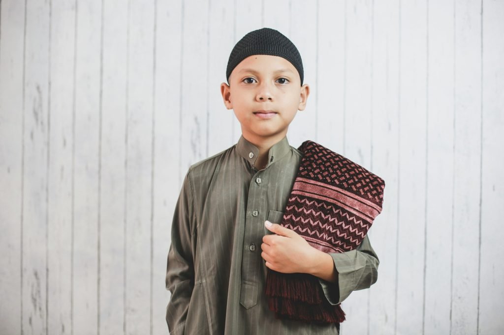 Muslim Boy with prayer mat on his shoulder